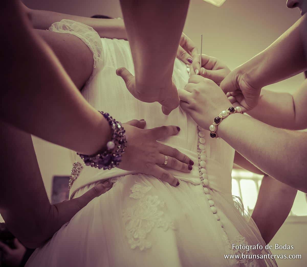 Amigas le abotonan el vestido a la novia.