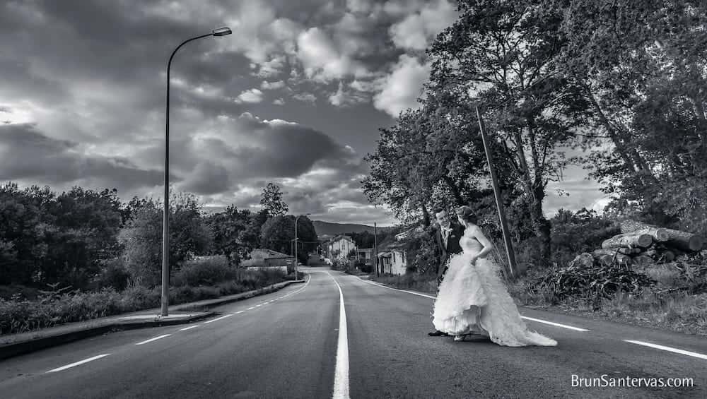 Novios cruzando carretera desierta.